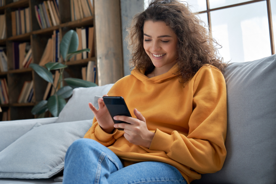 Nöjd kund sitter med sin telefon i sin soffa.